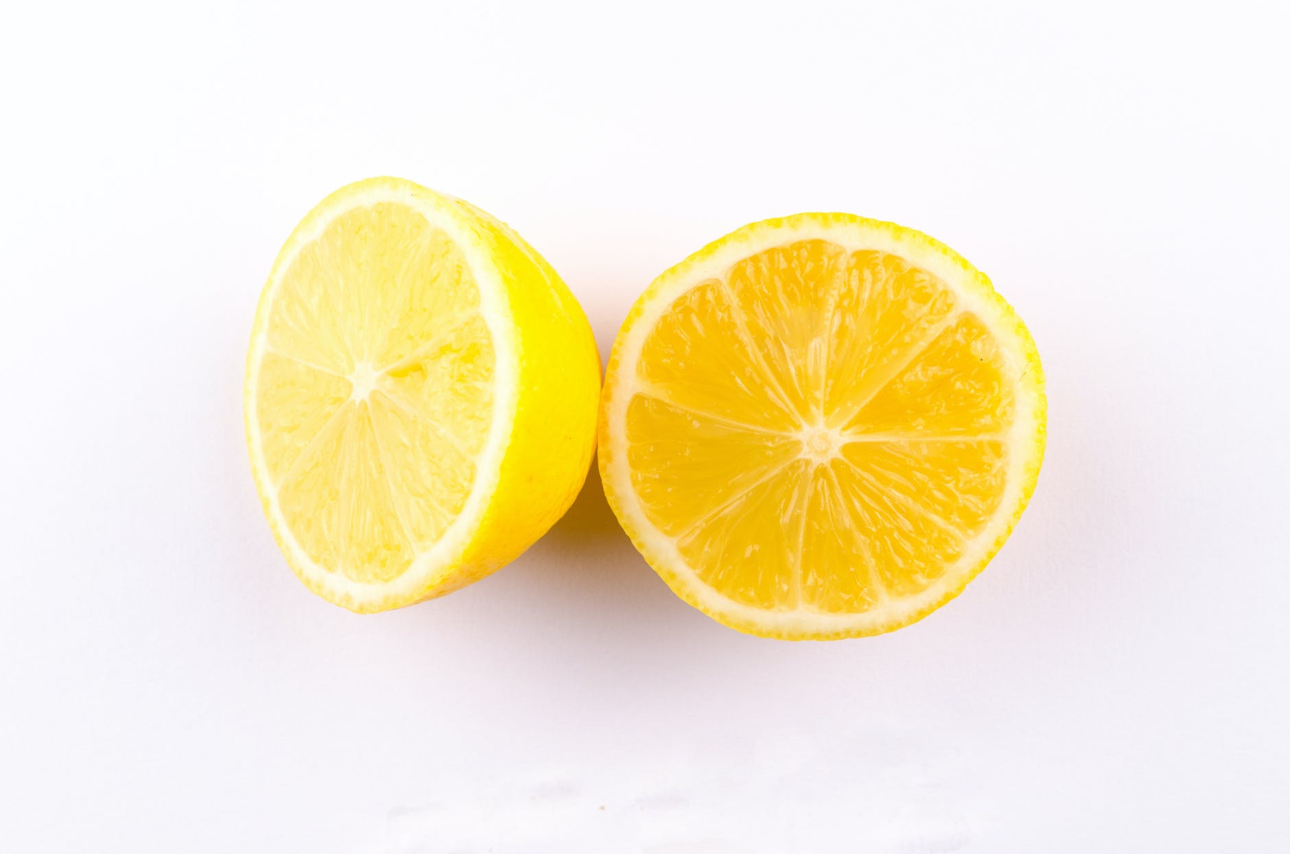 close up photo of sliced yellow lemon on white surface